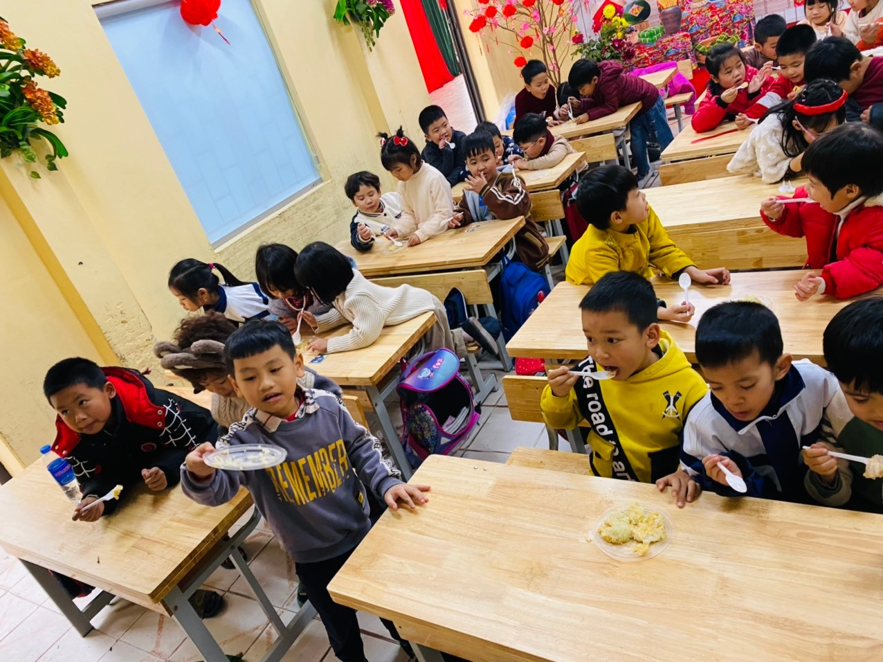 A group of children eating in a classroom  Description automatically generated